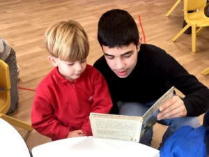 Alumnes d'Infantil i Secundària gaudint d'una estona de lectura compartida.